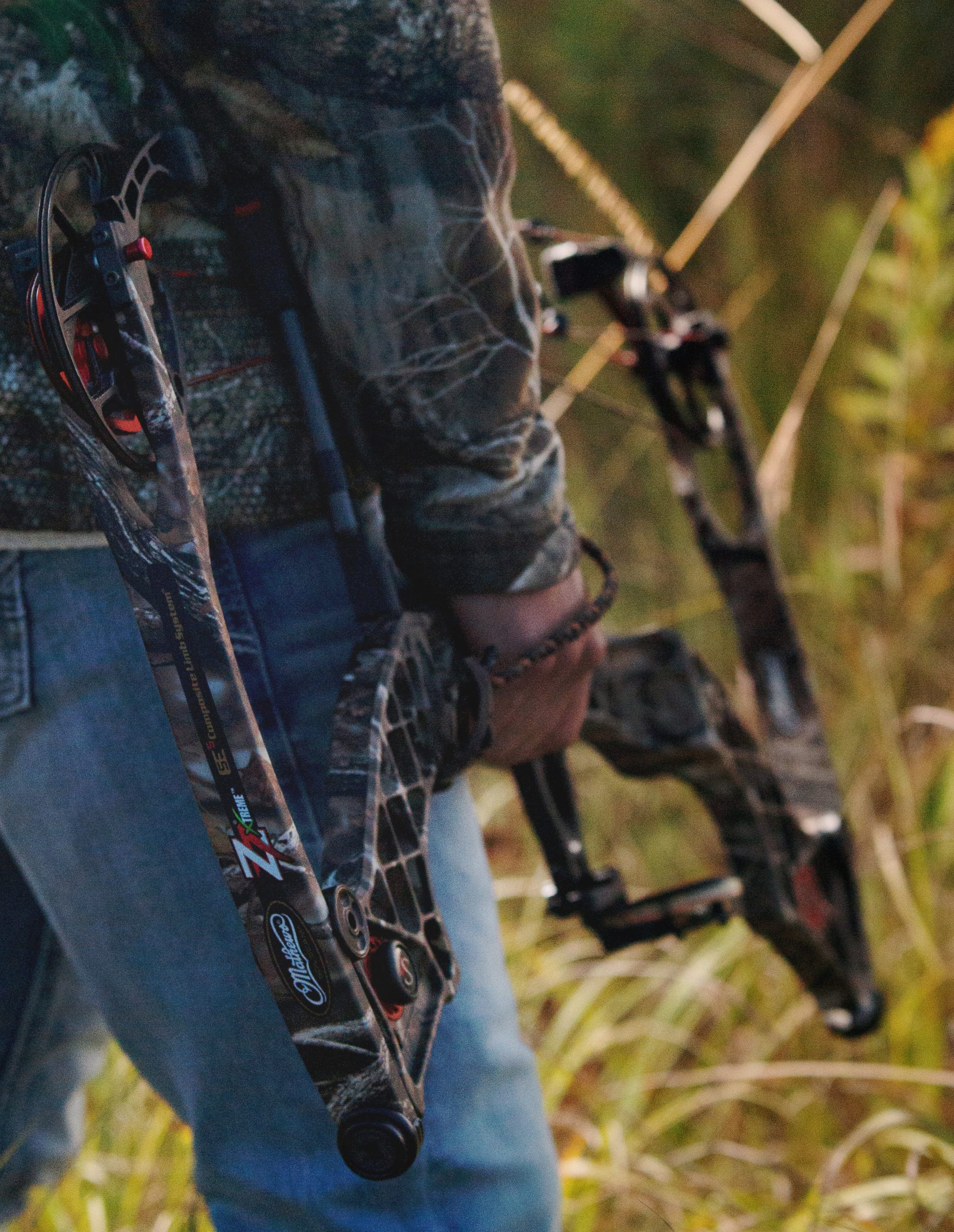 Detail of a high school senior boy with a bow by Teri Lynn Photography in Brodhead, WI. Close-up of a young man holding a compound bow, dressed in camouflage. Specialized senior portraits highlighting hobbies and personal interests.