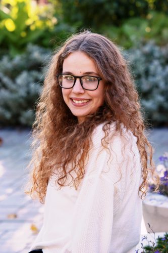 Senior picture of girl with long curly hair sitting in a garden