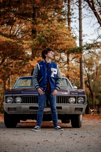 Young man wearing his Parkview letterman's jacket and posing with his vintage car in Beloit, WI
