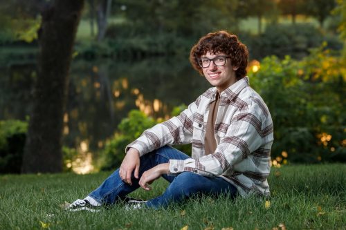 Young man sitting in front of a lake at sunset